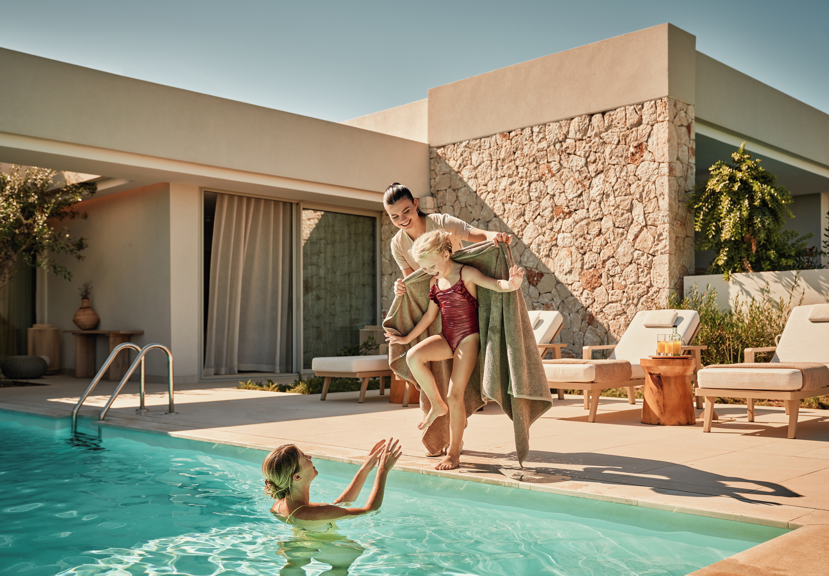 Family with children having fun together in the swimming pool at an Ikos resort